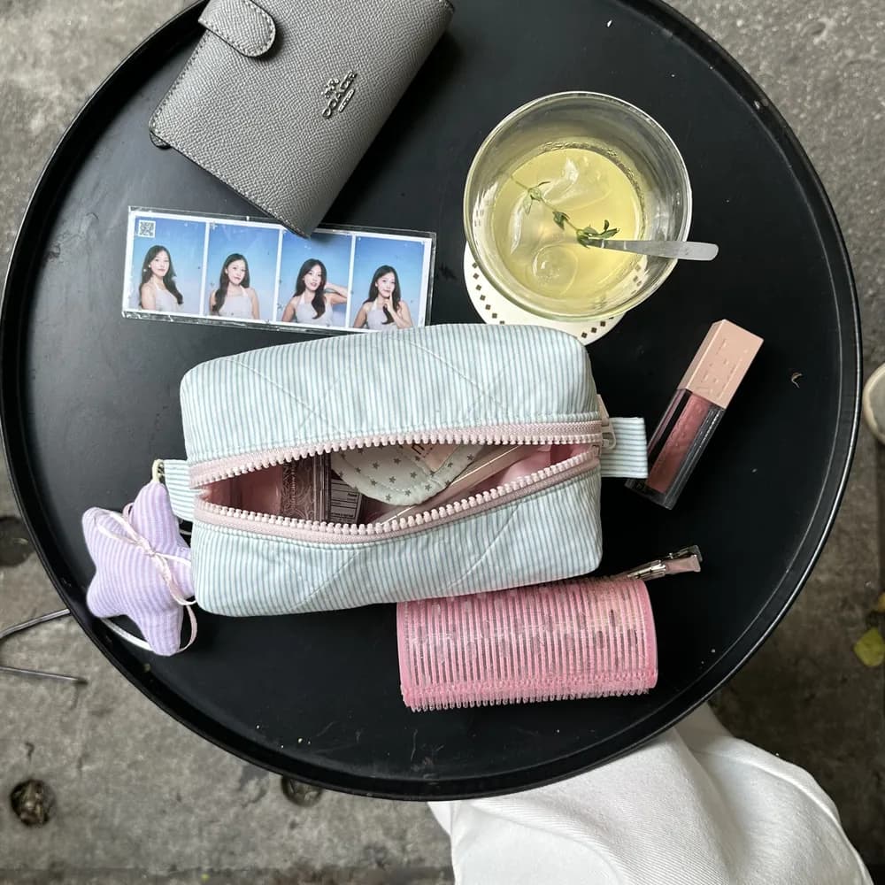 Pouch Blue Sky đựng son, ví và ảnh photobooth trên bàn cà phê
